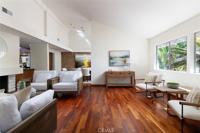 living area with dark wood-style floors, a fireplace, visible vents, and high vaulted ceiling