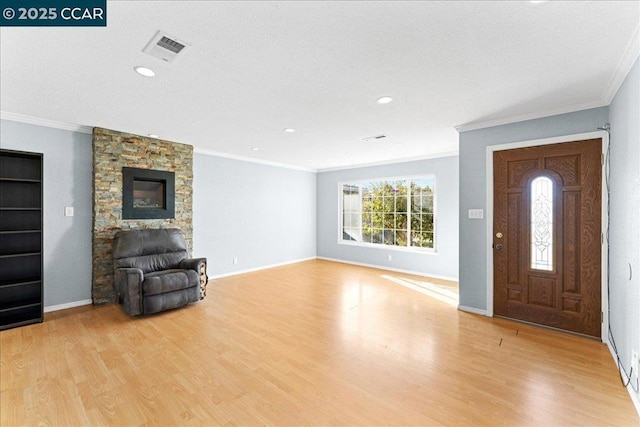 entryway featuring a fireplace, ornamental molding, and light hardwood / wood-style flooring