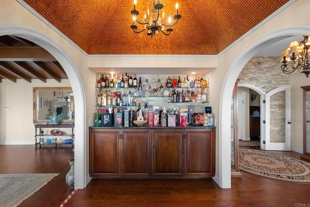 bar featuring a notable chandelier, lofted ceiling, dark stone counters, brick ceiling, and dark wood-type flooring