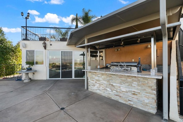 view of patio featuring an outdoor bar, area for grilling, and a balcony