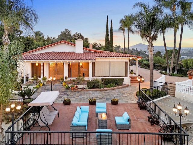 back house at dusk with a patio area and outdoor lounge area