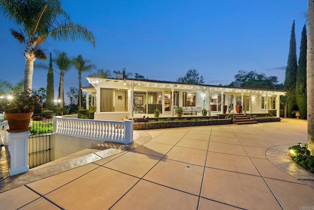 back house at dusk with a patio area