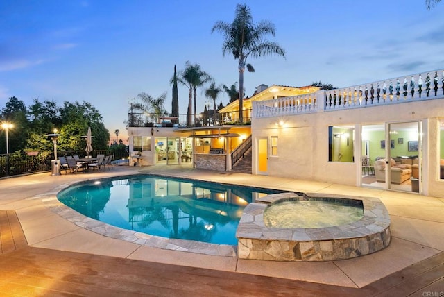 pool at dusk featuring exterior bar, an in ground hot tub, and a patio area