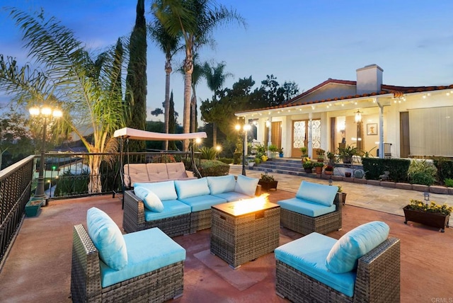 patio terrace at dusk featuring an outdoor living space with a fire pit