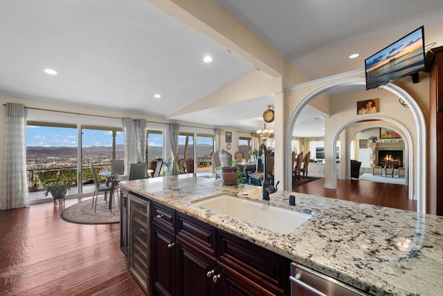 kitchen featuring light stone countertops, dark wood-type flooring, stainless steel dishwasher, and sink