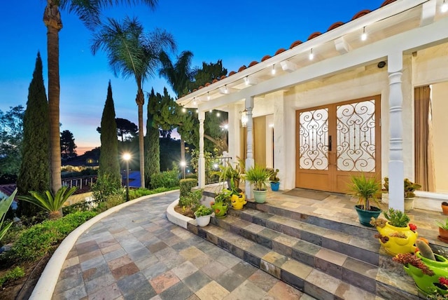 exterior entry at dusk with a patio area and french doors