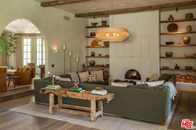 living room with hardwood / wood-style floors, a large fireplace, and beam ceiling