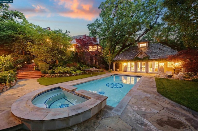 pool at dusk with a lawn, a patio, an outdoor structure, and an in ground hot tub