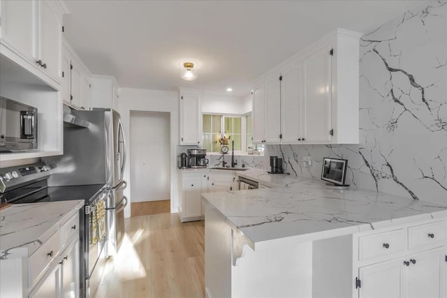 kitchen with light stone counters, white cabinetry, and appliances with stainless steel finishes