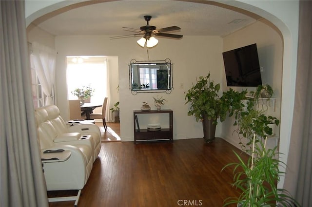 living area with dark wood-type flooring and ceiling fan