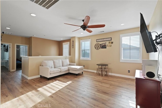 living room featuring ceiling fan, light hardwood / wood-style floors, and plenty of natural light