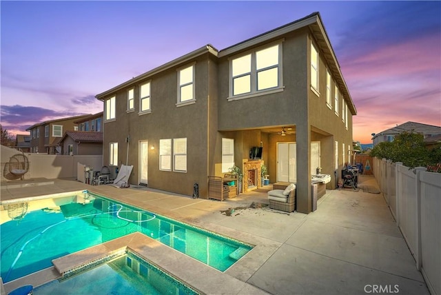 back house at dusk featuring a fenced in pool and a patio