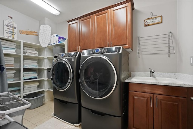 washroom featuring sink, light tile patterned flooring, washing machine and clothes dryer, and cabinets