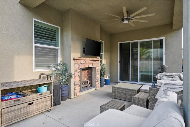 view of patio / terrace featuring ceiling fan and an outdoor living space with a fireplace