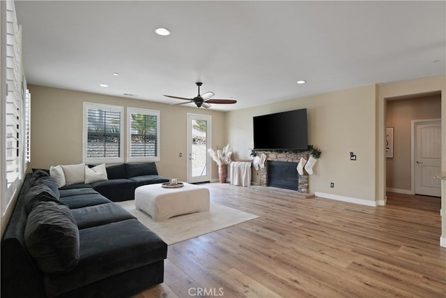 living room featuring a fireplace, light wood-type flooring, and ceiling fan