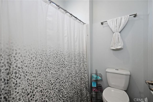 bathroom featuring toilet and curtained shower