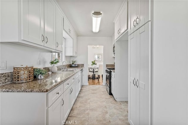 kitchen featuring sink, stainless steel appliances, dark stone countertops, and white cabinetry