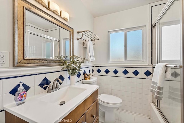 full bathroom featuring tile walls, shower / bath combination with glass door, vanity, and toilet