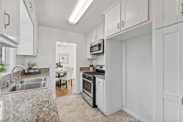 kitchen featuring stainless steel appliances, light stone countertops, white cabinetry, and sink