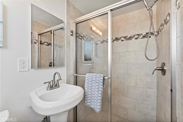 bathroom with a shower with shower door and sink