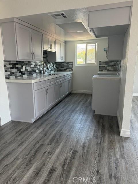 kitchen featuring washer / dryer, gray cabinets, dark hardwood / wood-style flooring, and sink