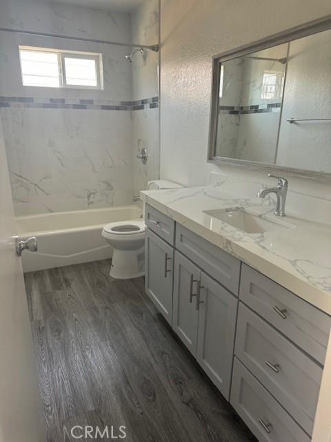 full bathroom with toilet, wood-type flooring, vanity, and tiled shower / bath combo