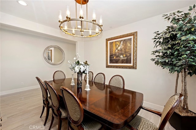 dining space with light hardwood / wood-style flooring and a chandelier