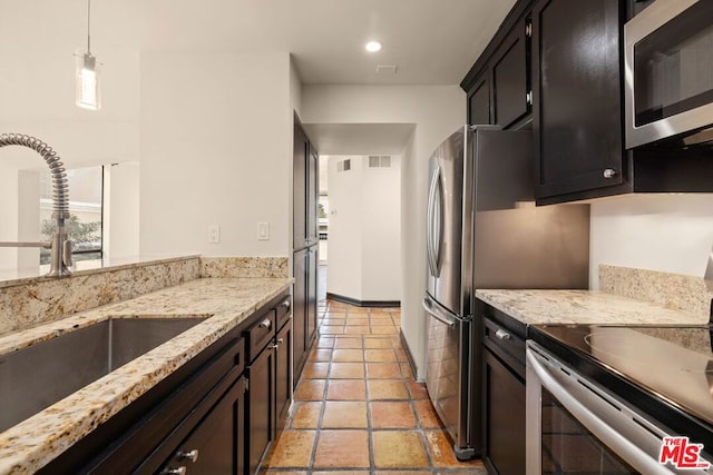 kitchen with light stone counters, pendant lighting, appliances with stainless steel finishes, light tile patterned flooring, and sink