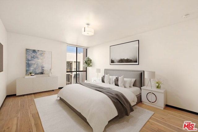 bedroom with light hardwood / wood-style floors and a wall of windows