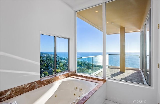 bathroom featuring a relaxing tiled tub and a water view