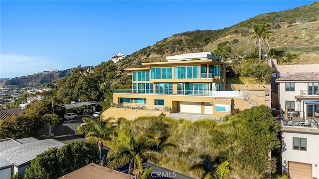 rear view of house with a balcony, a garage, and a mountain view