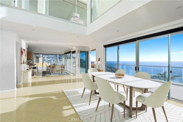 dining space with a water view, a towering ceiling, and light tile patterned floors