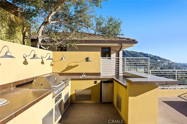 view of patio / terrace with an outdoor kitchen, a mountain view, and area for grilling