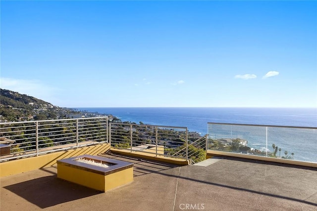 view of patio / terrace with a balcony, a fire pit, and a water view