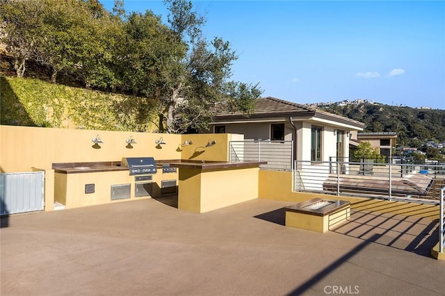 view of patio featuring exterior kitchen, a mountain view, and area for grilling