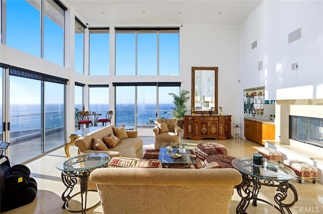 living room featuring a water view, a towering ceiling, and a high end fireplace