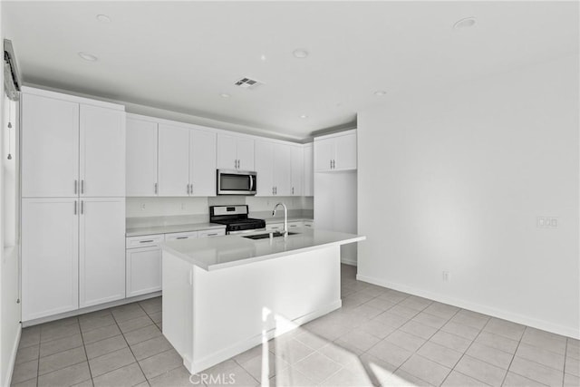 15992 Jamie Ln Unit 1, Fontana, CA 92336 - kitchen featuring appliances with stainless steel finishes, light countertops, light tile patterned floors, white cabinets, and an island with sink