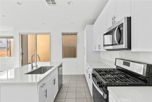 kitchen with light tile patterned floors, stainless steel appliances, white cabinetry, and sink