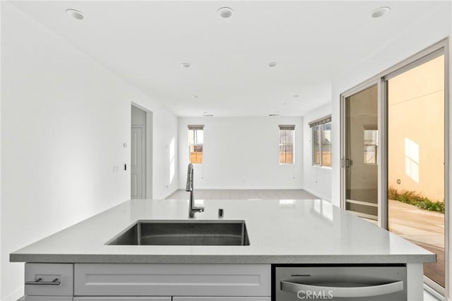 kitchen with a sink, dishwasher, open floor plan, and light countertops