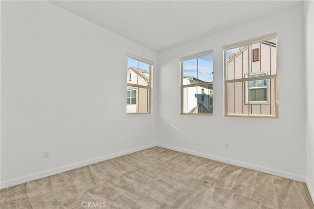 carpeted empty room featuring baseboards