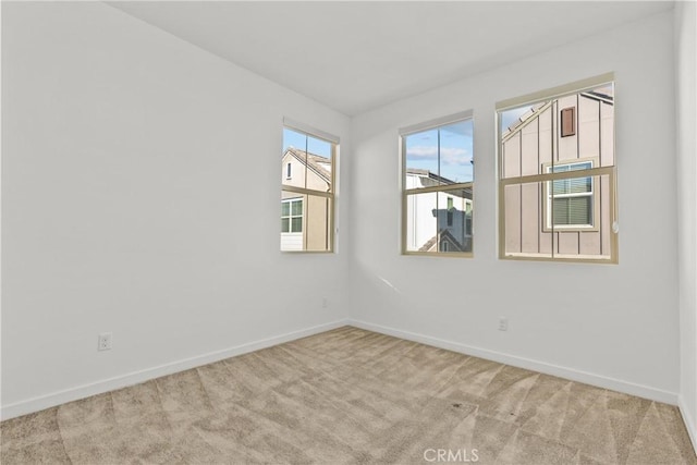 spare room with baseboards and light colored carpet