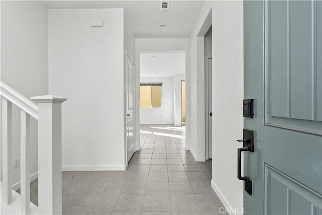 corridor with light tile patterned floors, baseboards, stairs, and visible vents