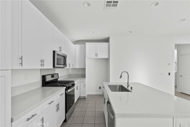 kitchen featuring a sink, visible vents, light countertops, appliances with stainless steel finishes, and a center island with sink