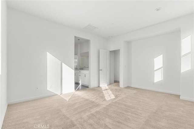 unfurnished bedroom featuring light carpet, connected bathroom, visible vents, and baseboards