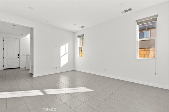 tiled empty room with visible vents and baseboards