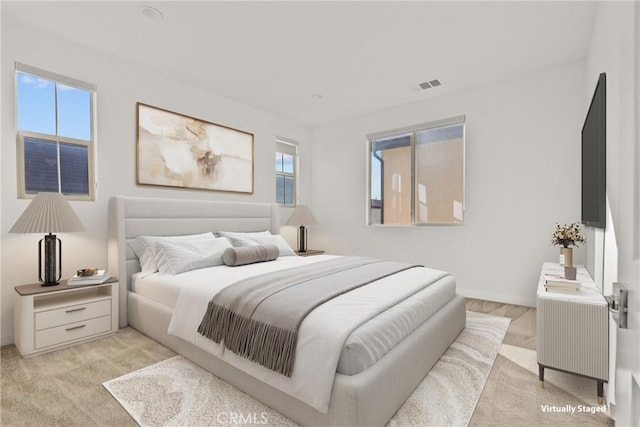 bedroom with baseboards, light colored carpet, and visible vents
