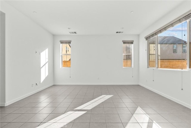 tiled spare room featuring visible vents and baseboards