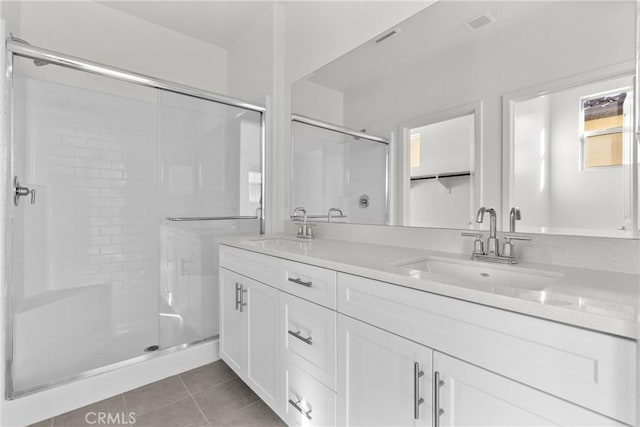 bathroom with double vanity, a sink, a shower stall, and tile patterned floors