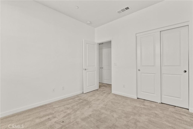 unfurnished bedroom with baseboards, visible vents, a closet, and light colored carpet