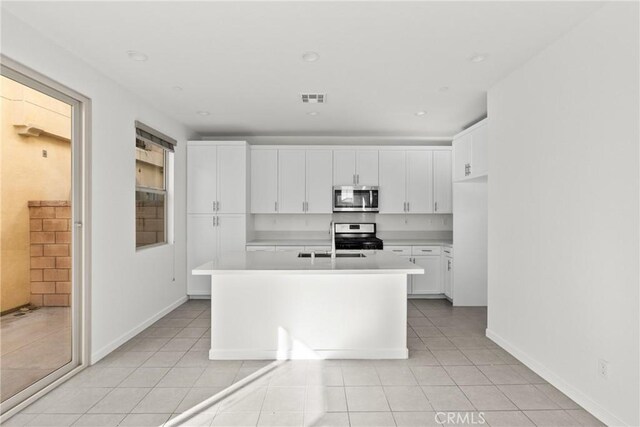 kitchen with a sink, visible vents, white cabinetry, light countertops, and appliances with stainless steel finishes